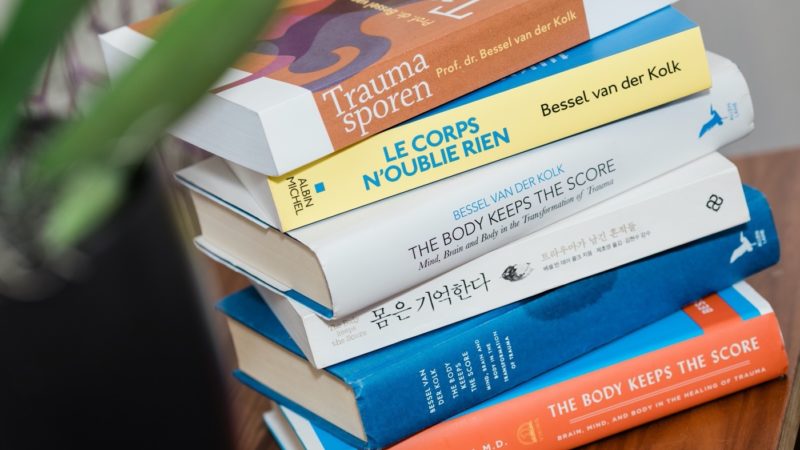 A stack of books. The Body Keeps the Score in various languages.